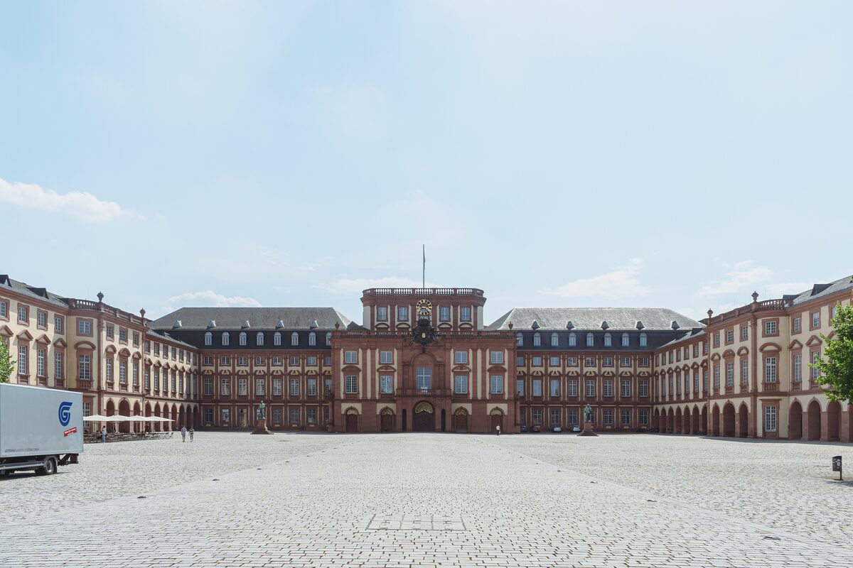 The wide Baroque front of Mannheim Palace across its paved courtyard