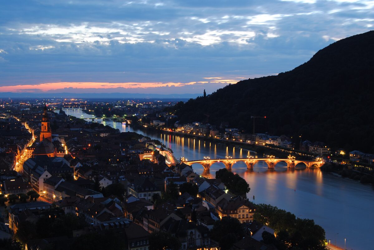 The lit Old Bridge and the old town along the Neckar at dusk, seen from above