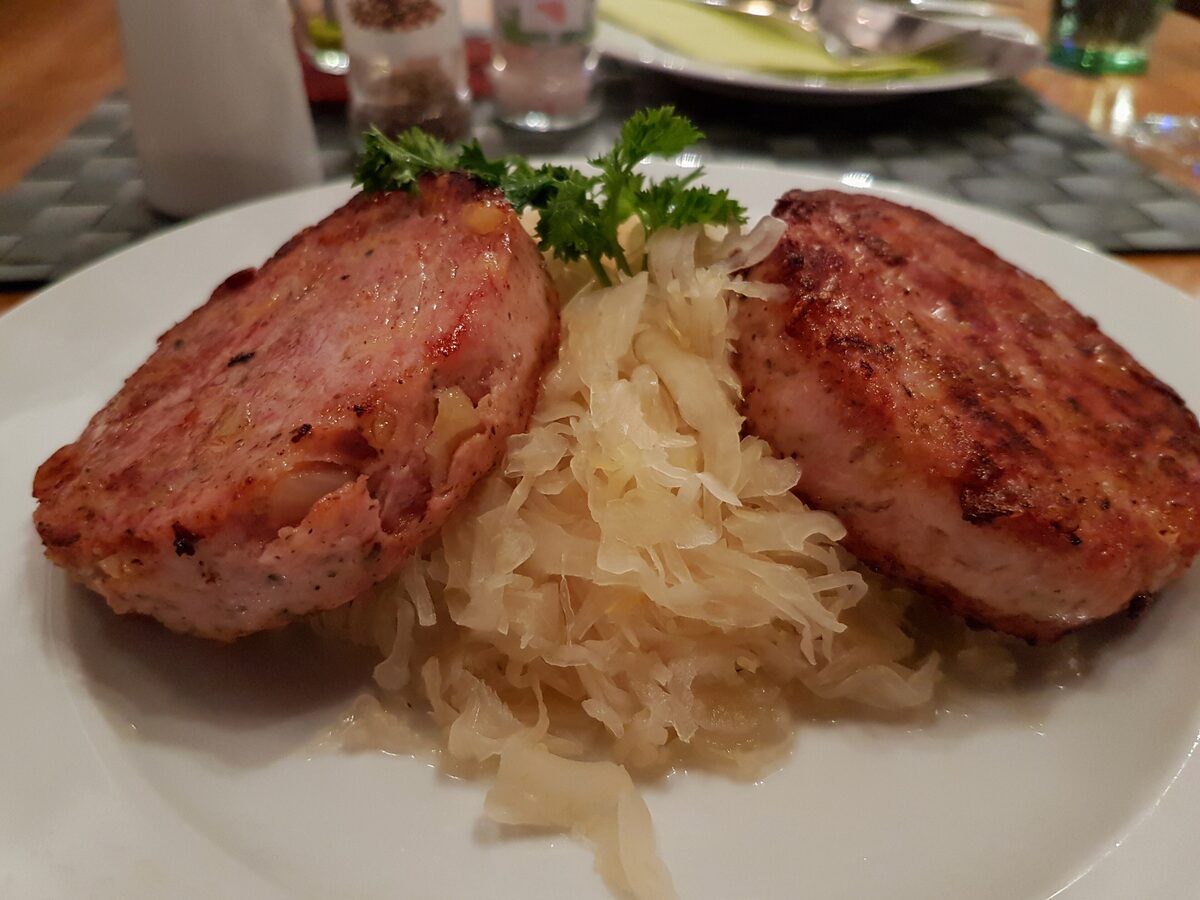 Two grilled slices of Saumagen on a bed of sauerkraut