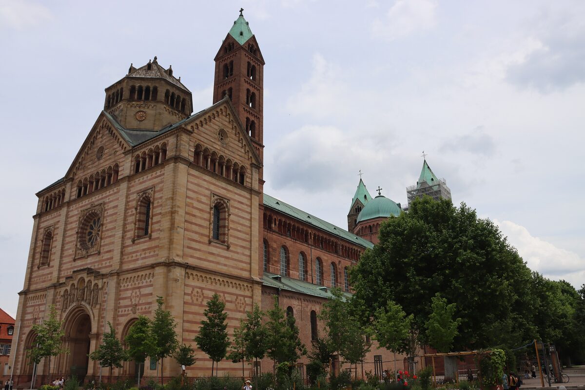 The sandstone west front and towers of Speyer Cathedral rising behind trees