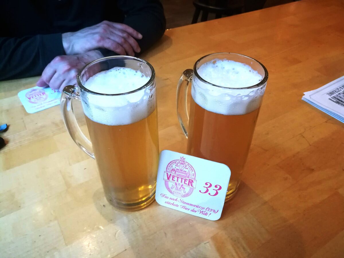 Two glasses of beer on a wooden table with a Vetter 33 beer mat