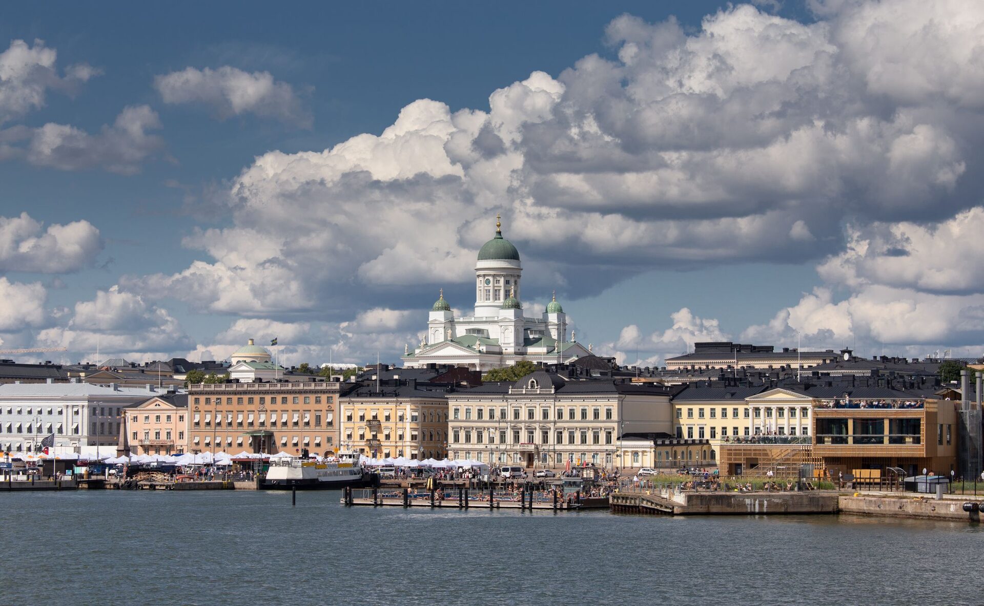Helsinki's waterfront seen from the sea, with the white Helsinki Cathedral and its green dome rising above a row of pale buildings