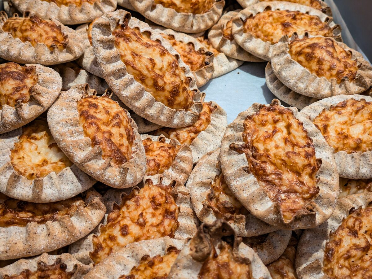 A pile of oval Karelian pies with crimped rye crusts and golden rice filling