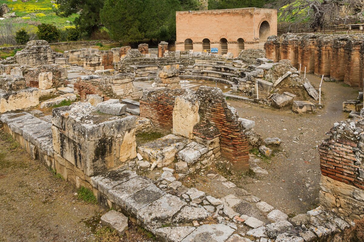 The small Roman odeon of Gortyna, a semicircle of stone seats and columns among olive trees
