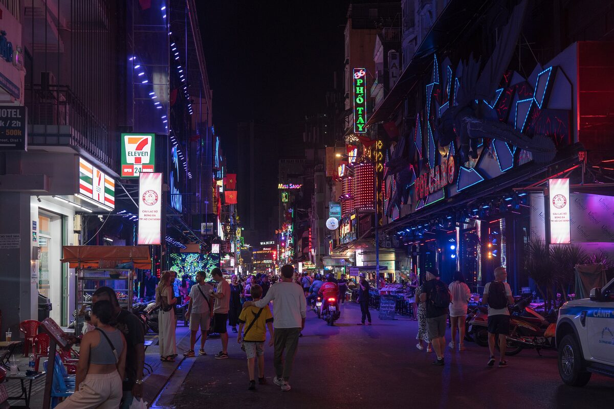 Bùi Viện Street at night, with neon signs, bars and people walking in the road