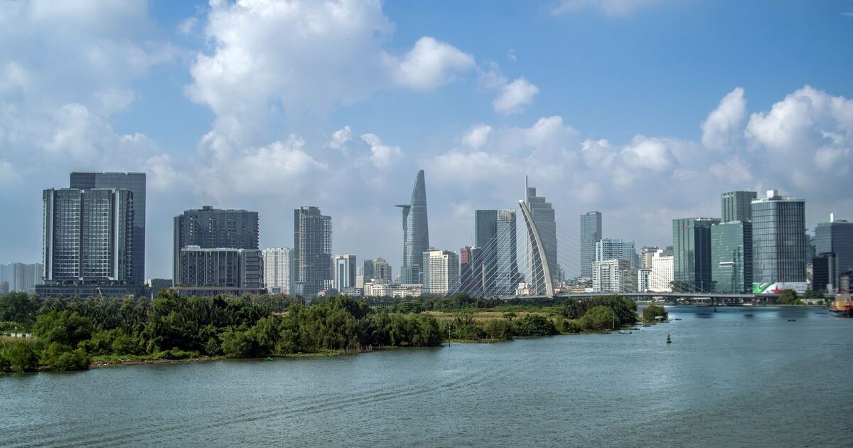The Ho Chi Minh City skyline with Bitexco Tower, seen across the Saigon River under a blue sky