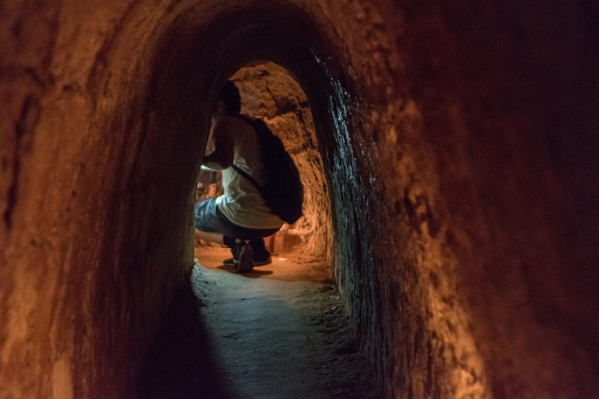 A low, narrow tunnel with a visitor crouching inside, showing how small the passages were