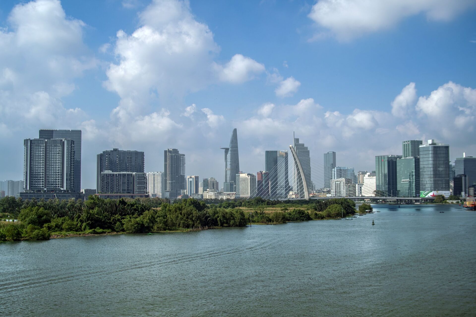 The Ho Chi Minh City skyline with Bitexco Tower, seen across the Saigon River under a blue sky