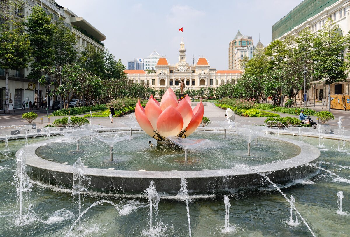 The lotus fountain on Nguyễn Huệ Street with the City Hall building behind it
