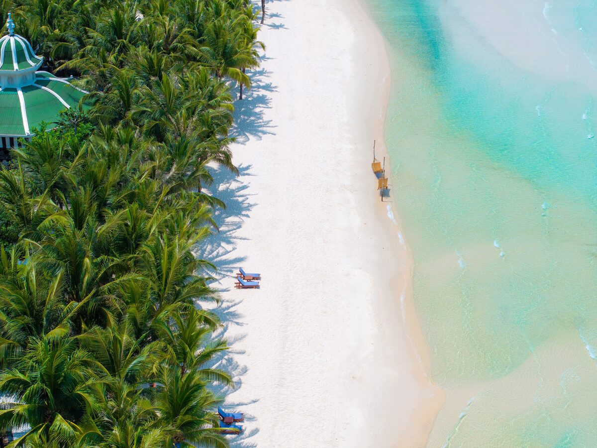 Aerial view of a white sand beach lined with palm trees and turquoise water on Phú Quốc