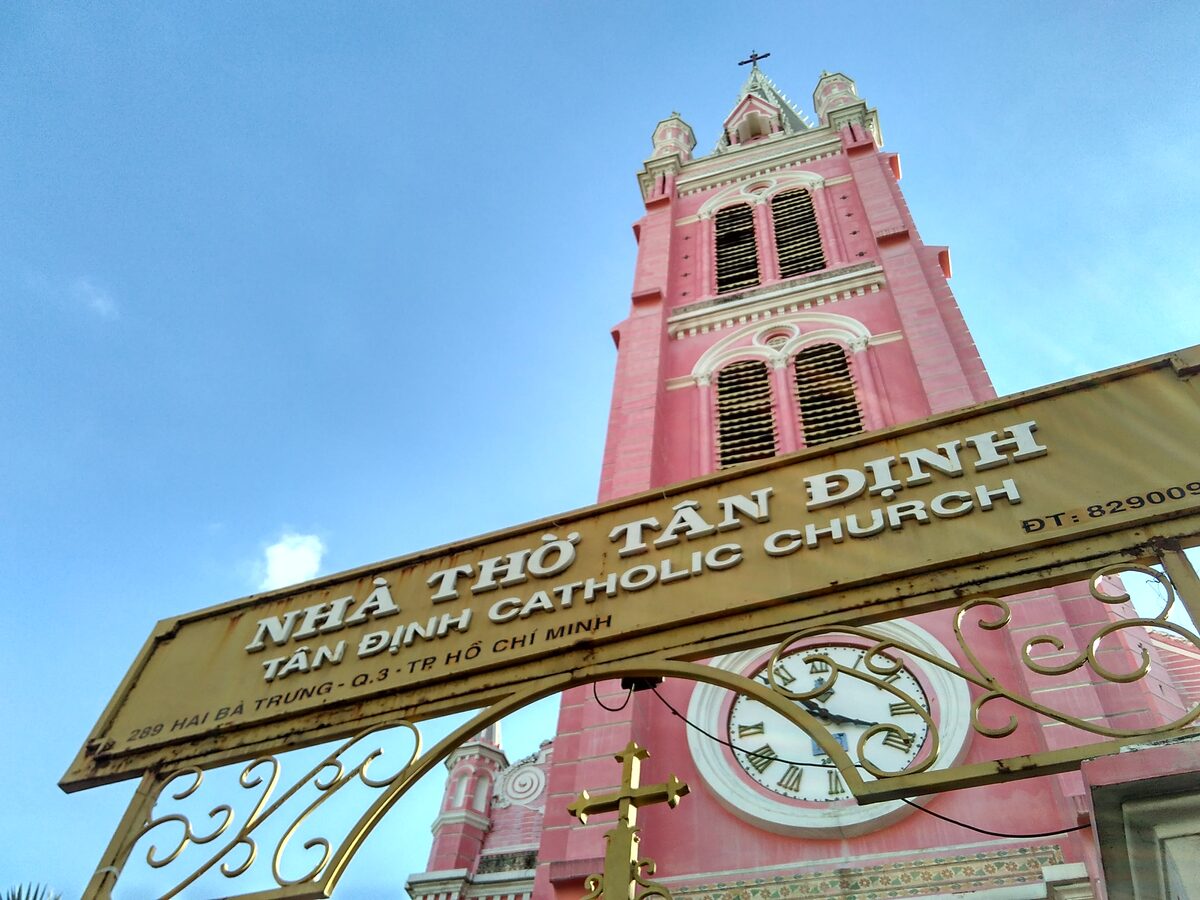 The pink bell tower of Tân Định Church, with its church name sign in the foreground