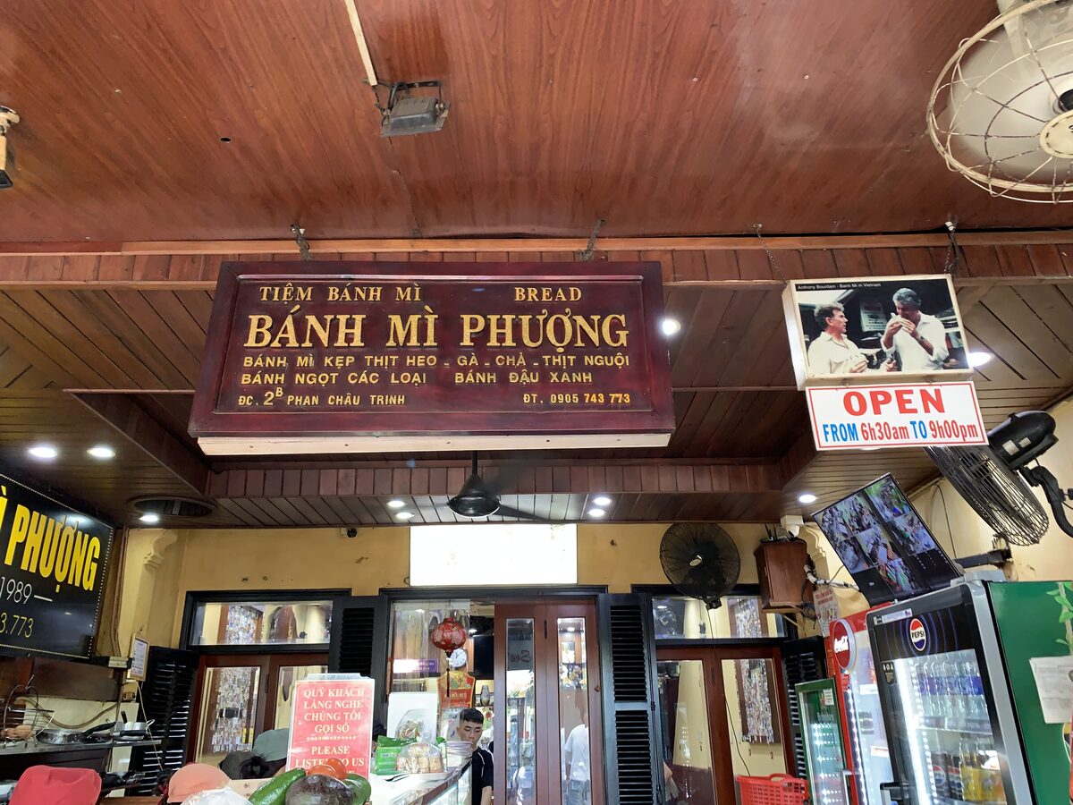 Inside Banh Mi Phuong, with its red sign above the counter and glass cases of fillings