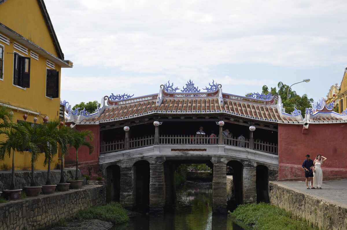 The Japanese Covered Bridge with its tiled roof and blue-white ridge ornaments, red end walls and yellow houses beside the creek