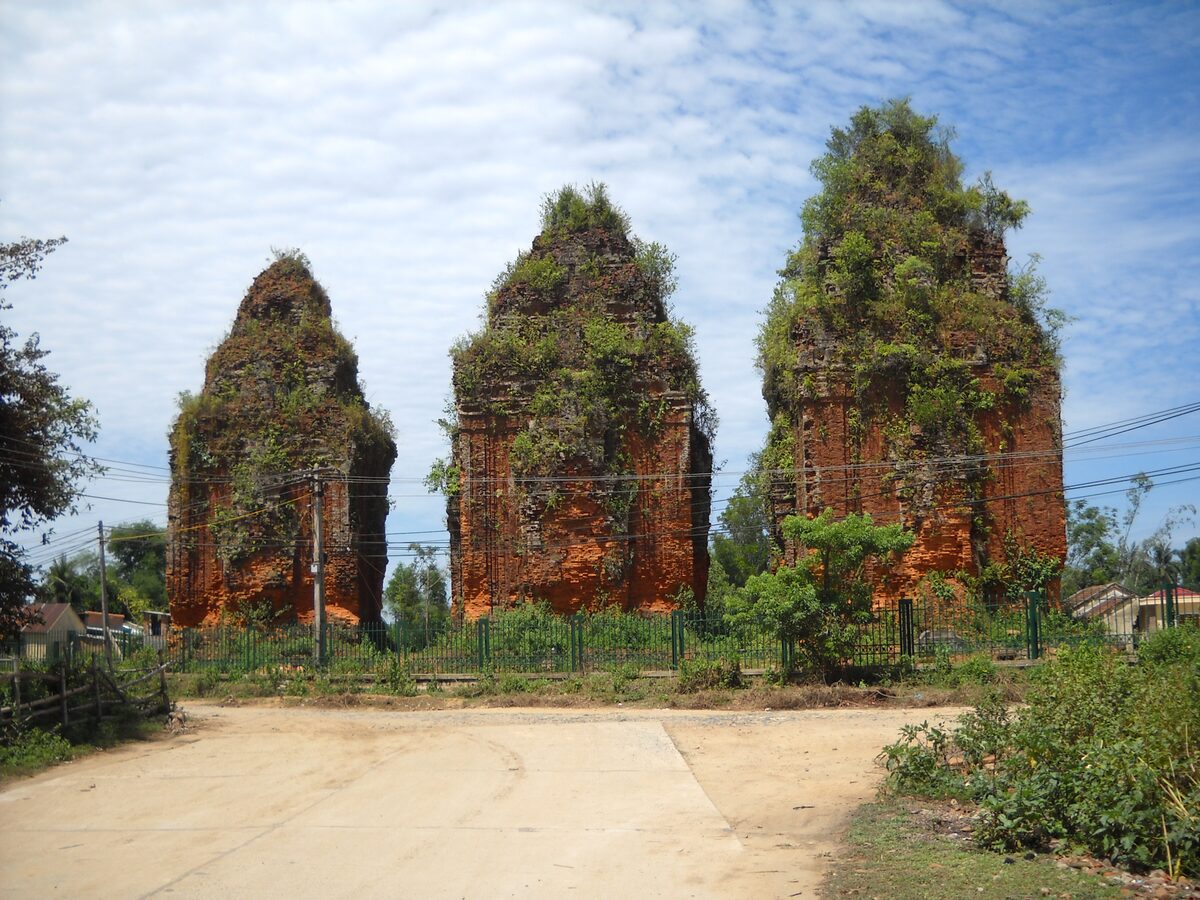 The three brick Khuong My Cham towers standing in a dusty yard under a blue sky