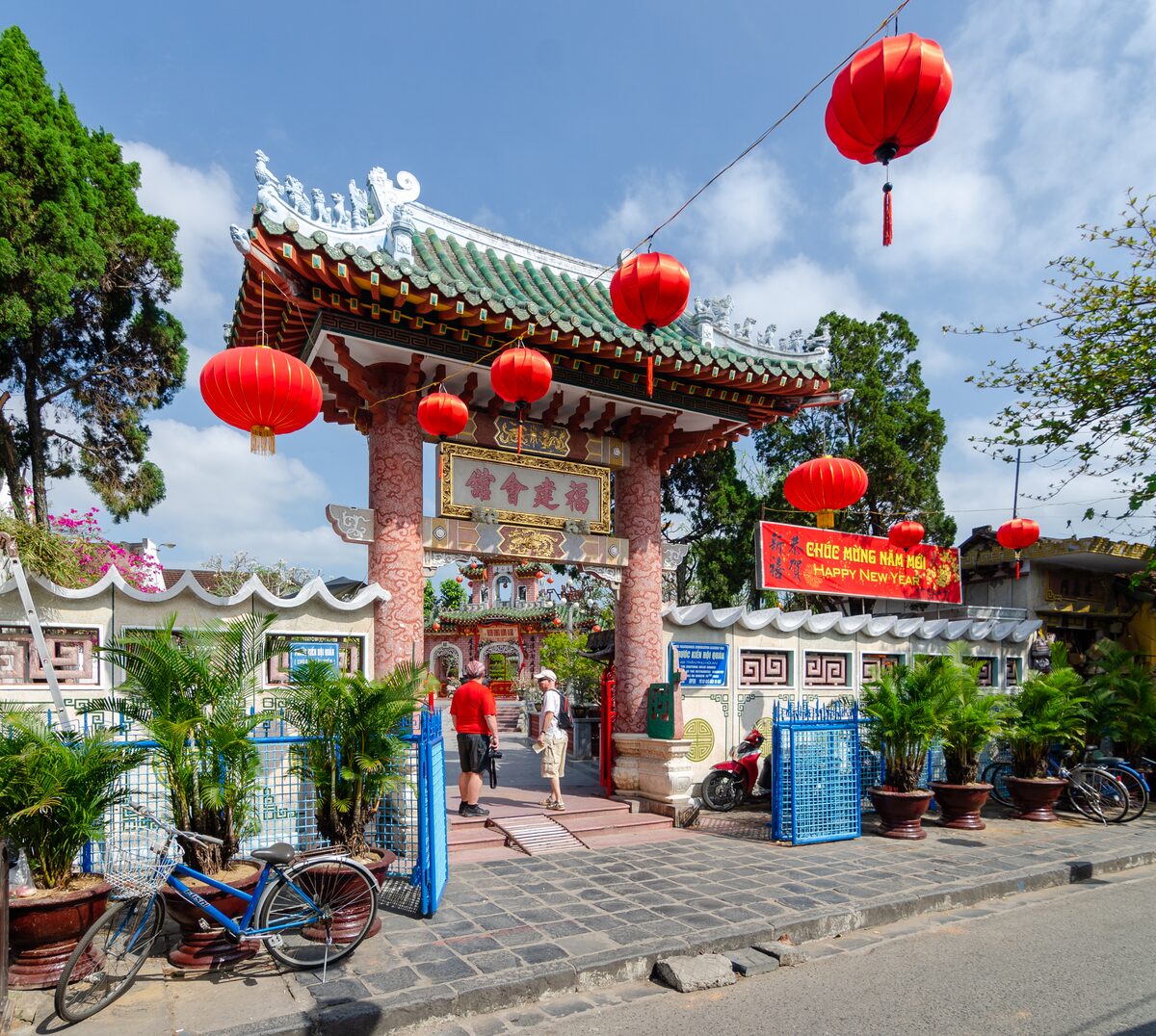 Red lanterns hang at the gate of the Fujian Assembly Hall, a green-roofed gateway on a sunny street