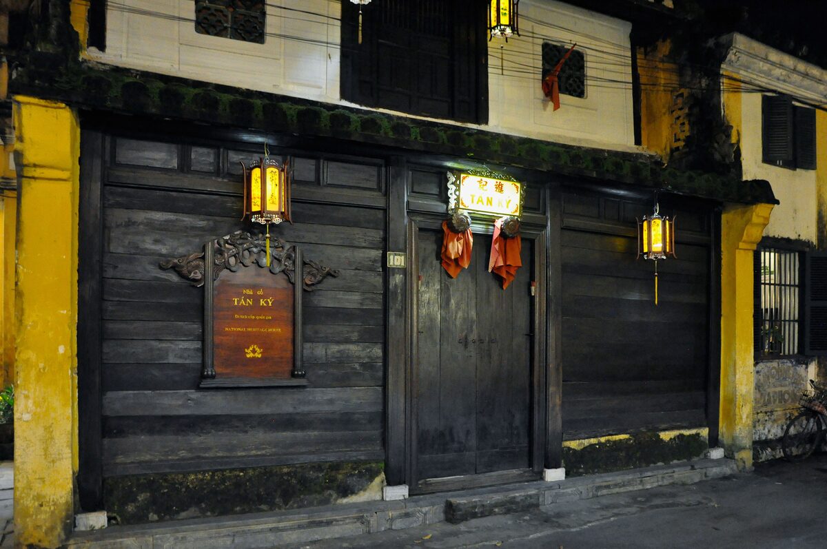 The dark wooden facade of the Tan Ky Old House, with a lantern hanging beside the door
