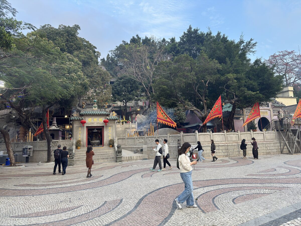The forecourt of A-Ma Temple in Macau with its wave-patterned pavement, red flags and old banyan trees