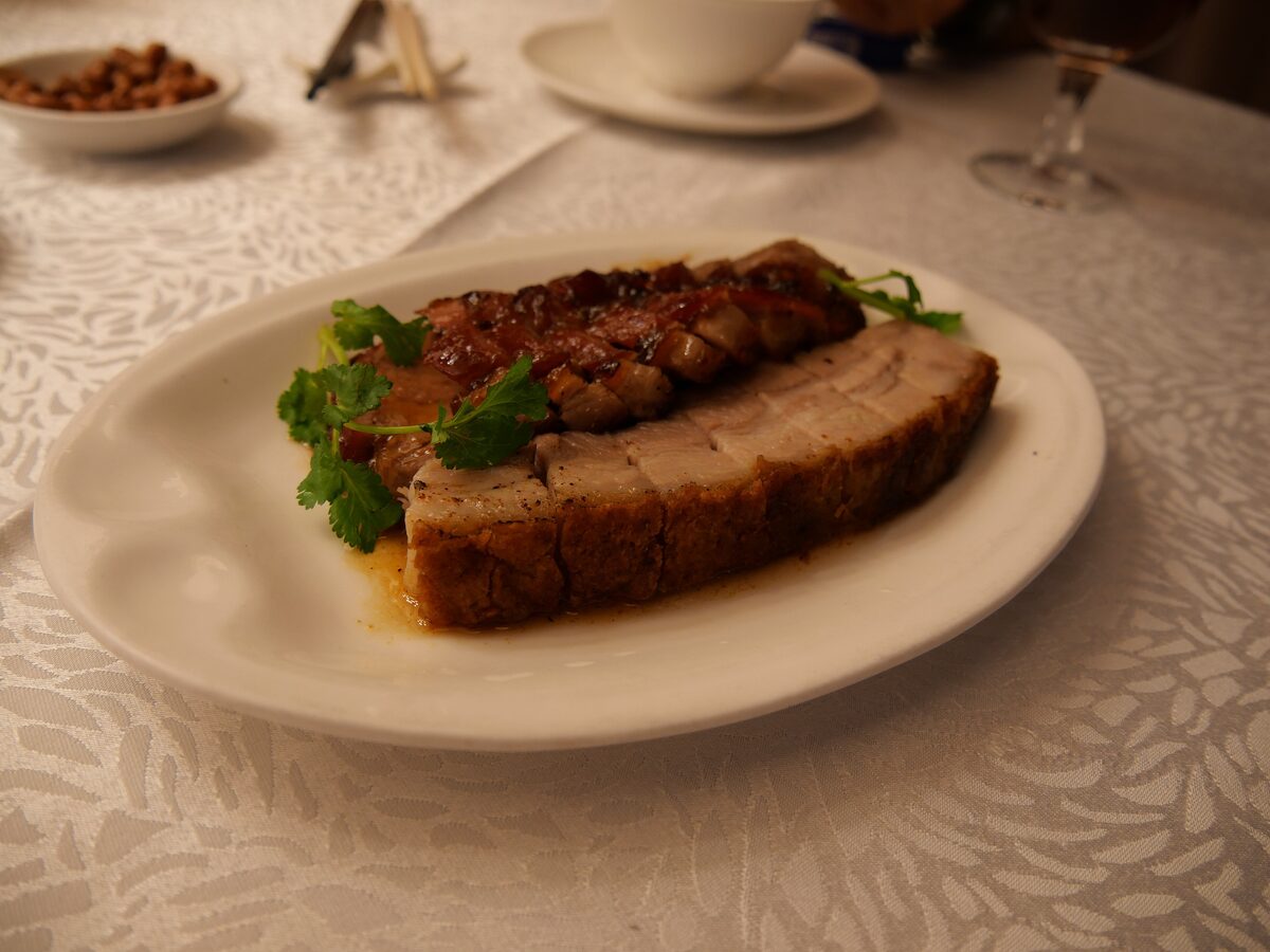 A plate of sliced char siu and crackling roast pork belly with garnish