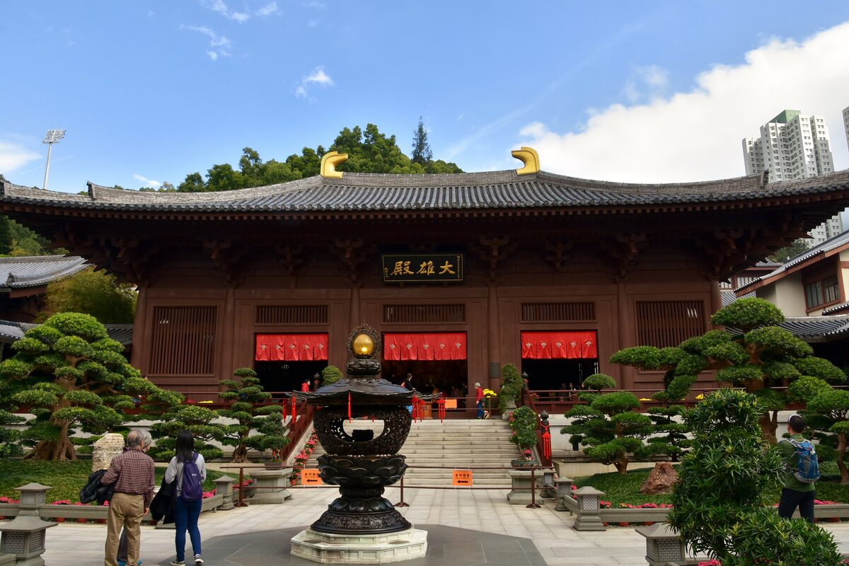 The main hall of Chi Lin Nunnery, a dark timber Tang-style building with an incense burner and clipped pines in front