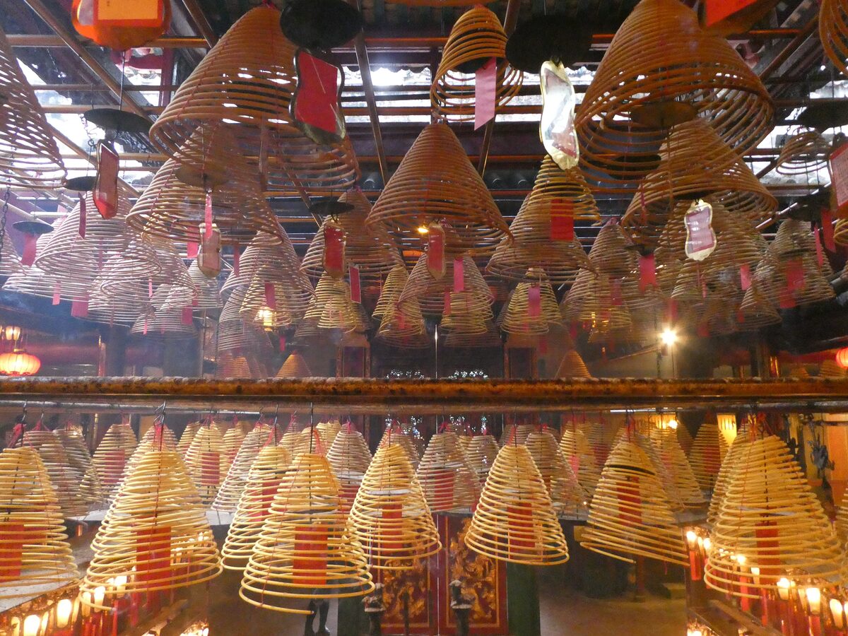 Rows of large spiral incense coils hanging from the ceiling of Man Mo Temple, glowing in the dim light