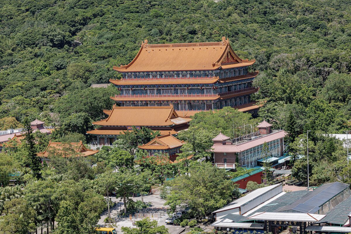 The tiered orange roofs of Po Lin Monastery's main hall among forested hills, seen from above