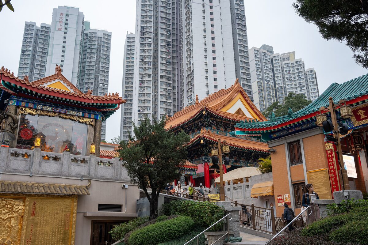 Colorful tiled roofs of Wong Tai Sin Temple with apartment towers rising right behind them