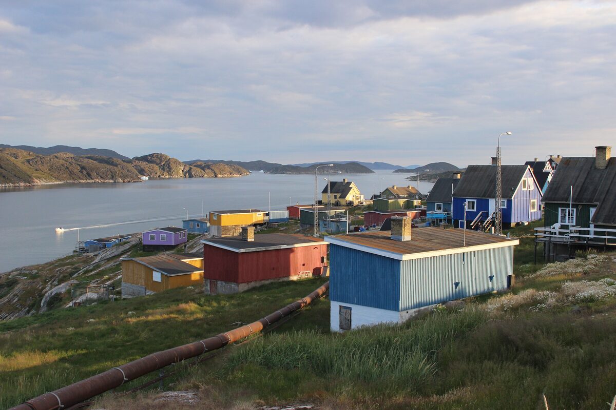 Colored houses along the shore at Qasigiannguit, with a bay and low hills behind