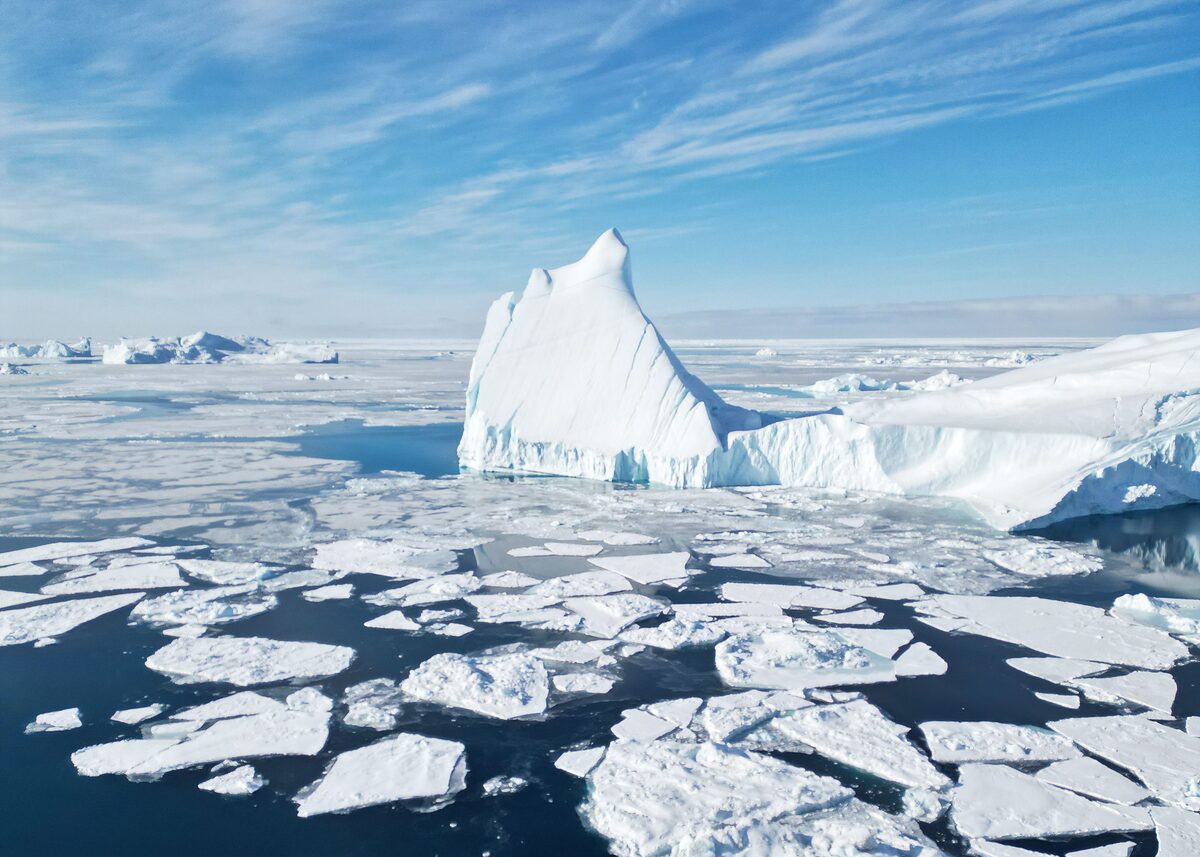 Broken sea ice and a tall iceberg in the Ilulissat Icefjord under a blue sky