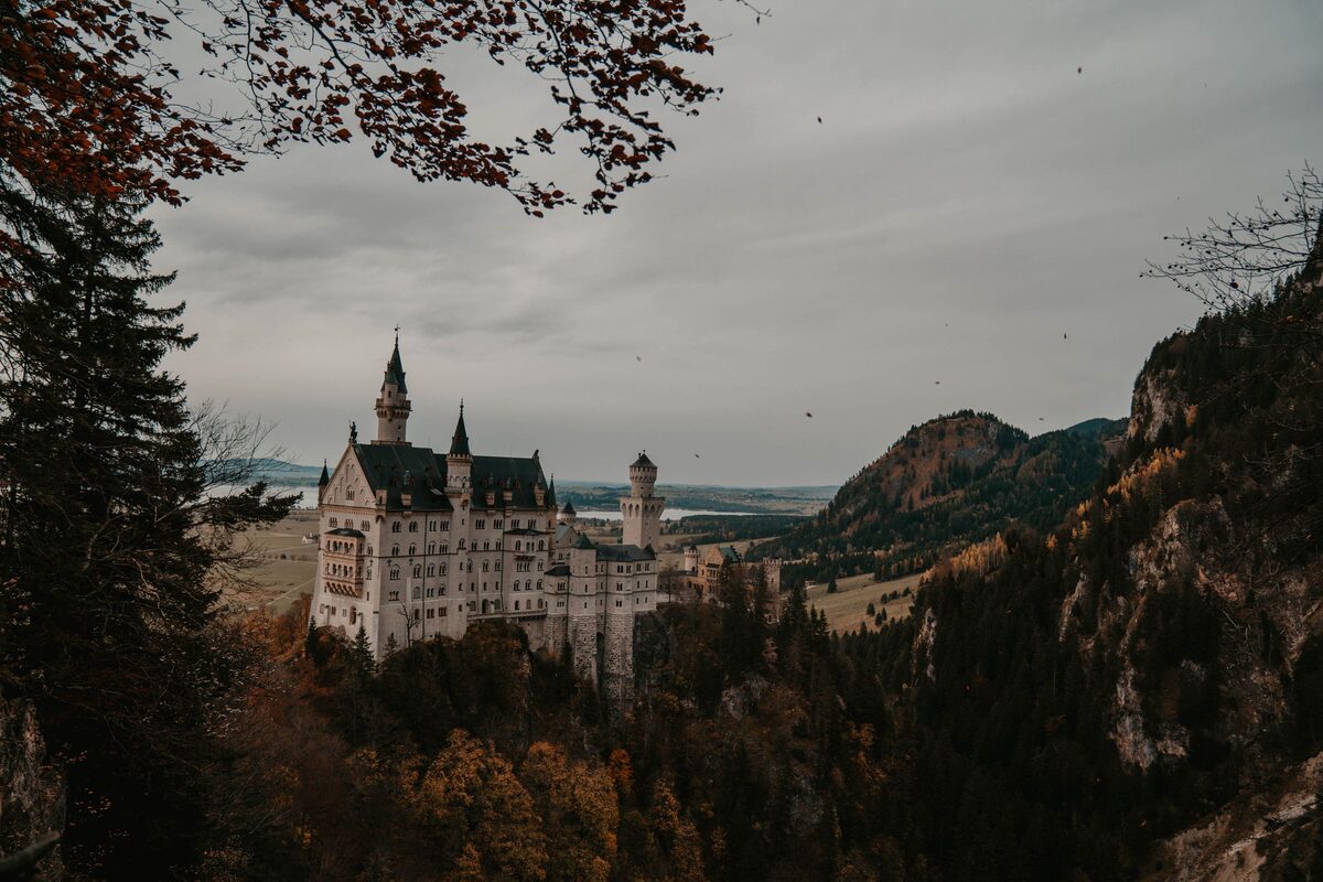 Neuschwanstein Castle with its white towers among autumn forest and cliffs