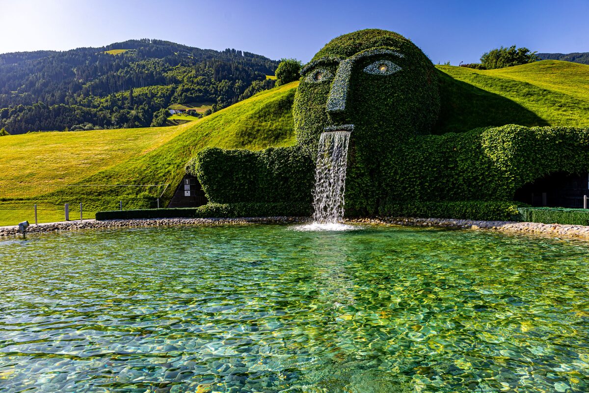The grass-covered giant's head with crystal eyes and a waterfall pouring from its mouth into a pool at the Swarovski Crystal Worlds