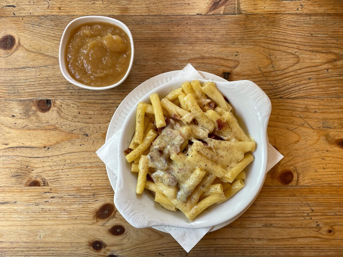 A bowl of Älplermagronen with apple sauce on a wooden table
