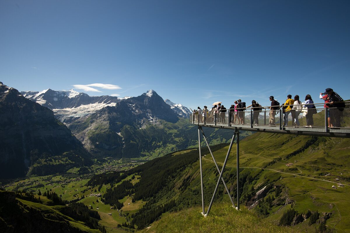 Visitors on the Cliff Walk at First, a steel walkway on the cliff with the mountains of the Eiger area beyond