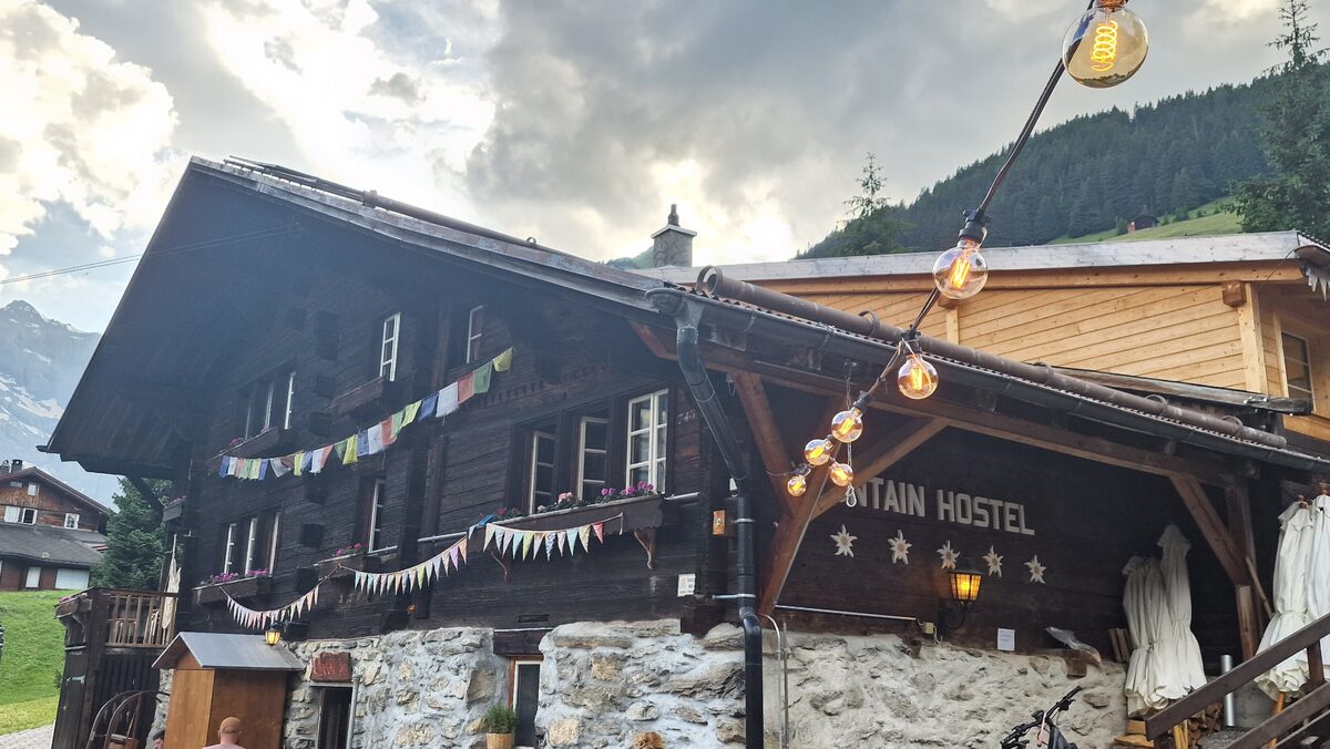 The Mountain Hostel in Gimmelwald, a timber chalet with prayer flags and string lights