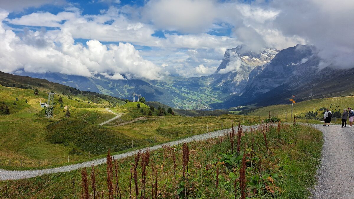 A gravel path across the meadows near Kleine Scheidegg, with high peaks rising behind clouds