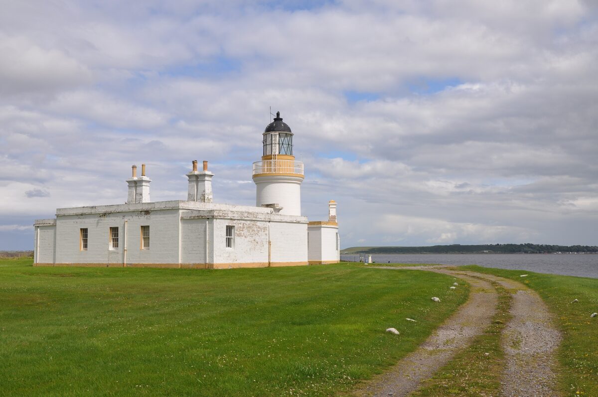 Chanonry Point lighthouse, a white tower and keeper's cottage on a green point at the edge of the Moray Firth