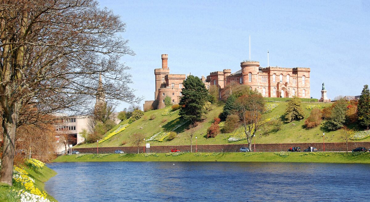 Inverness Castle, a pink sandstone castle with turrets on a green hill above the River Ness