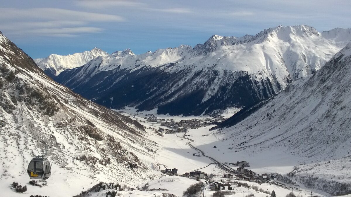 Galtür in winter, with snowy slopes, a gondola cabin and the village in the valley