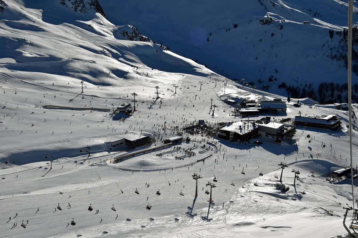 Winter overview of the Idalp with its pistes, lift lines and mountain restaurants under snowy ridges