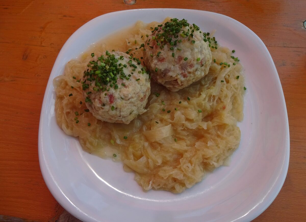 Two bacon dumplings on sauerkraut with chives on a white plate