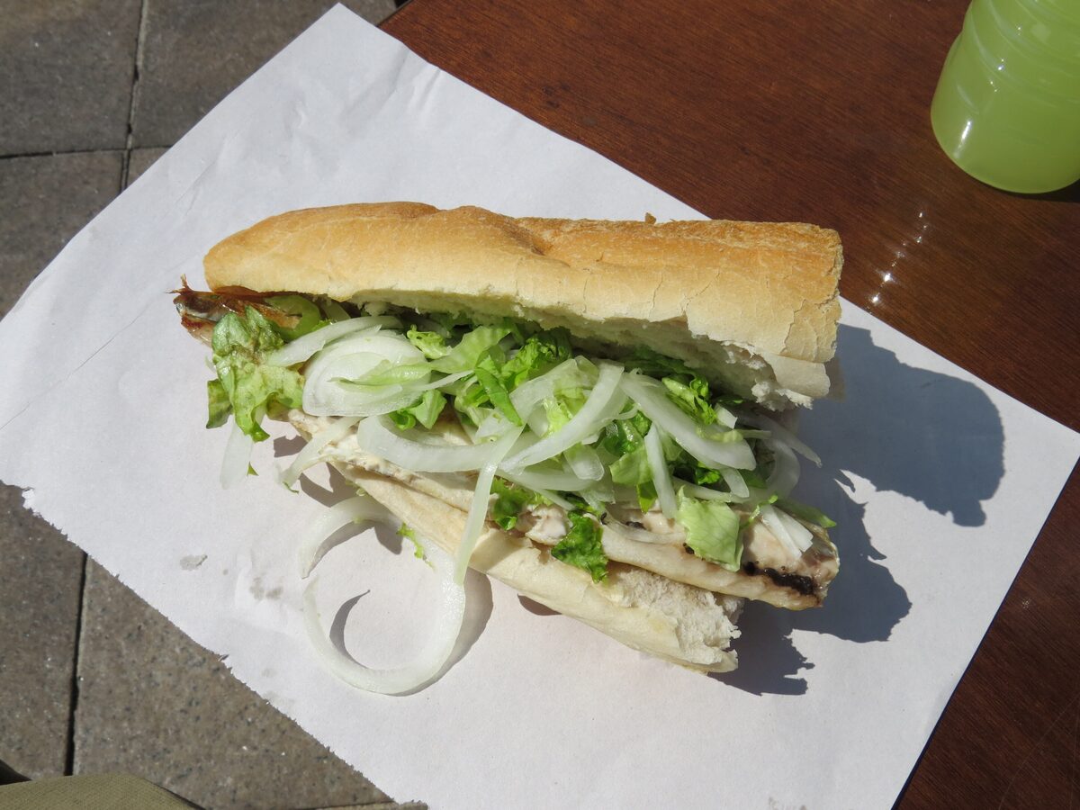 A balık ekmek fish sandwich of grilled fish, lettuce and onion in bread on paper, on a table in Istanbul