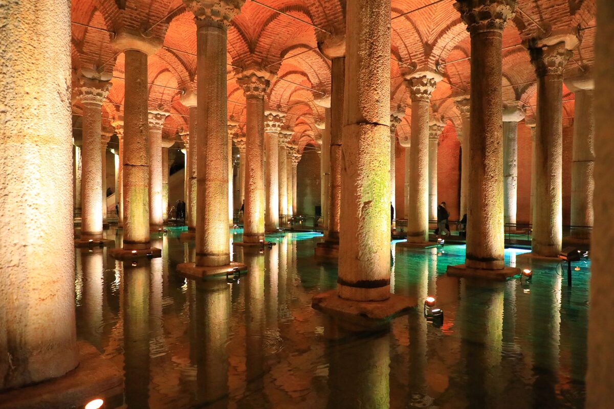 Rows of lit marble columns under brick vaults, reflected in the water of the Basilica Cistern