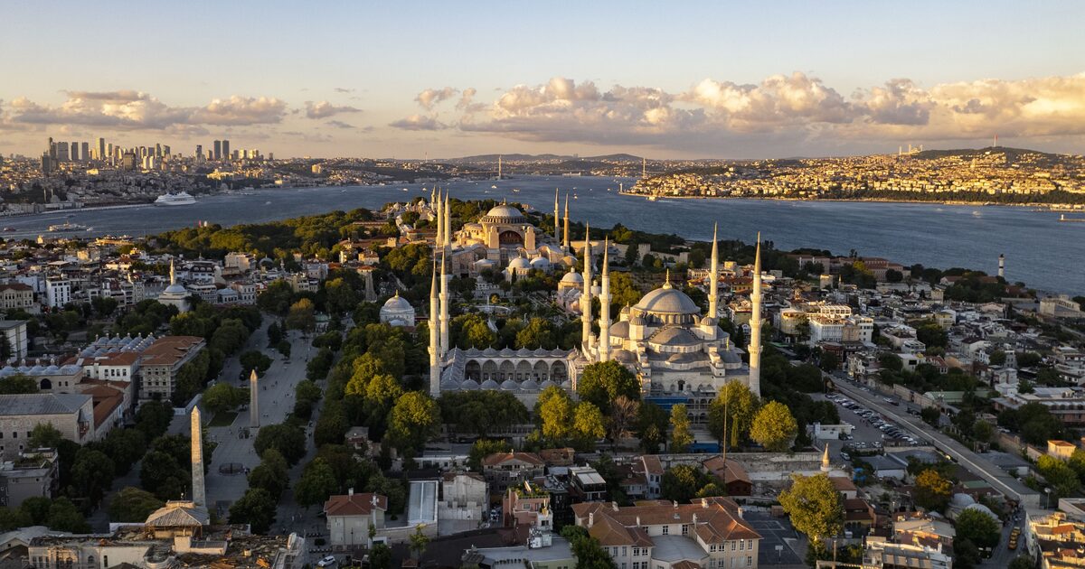 Aerial view of Sultanahmet at golden hour, with the Blue Mosque and its six minarets in front, Hagia Sophia behind it and the Bosphorus and the Asian shore beyond
