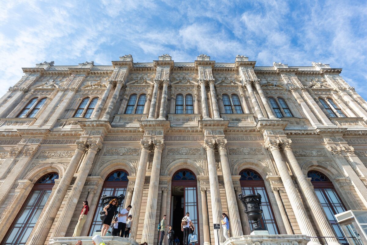 The ornate cream stone facade of Dolmabahçe Palace with columns and tall arched windows
