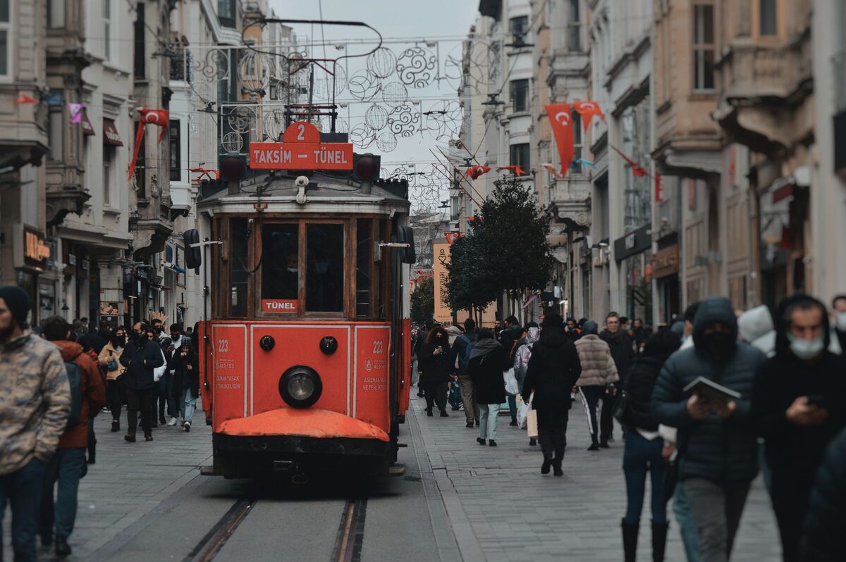 The red nostalgic tram running down a crowded İstiklal Avenue lined with 19th-century buildings