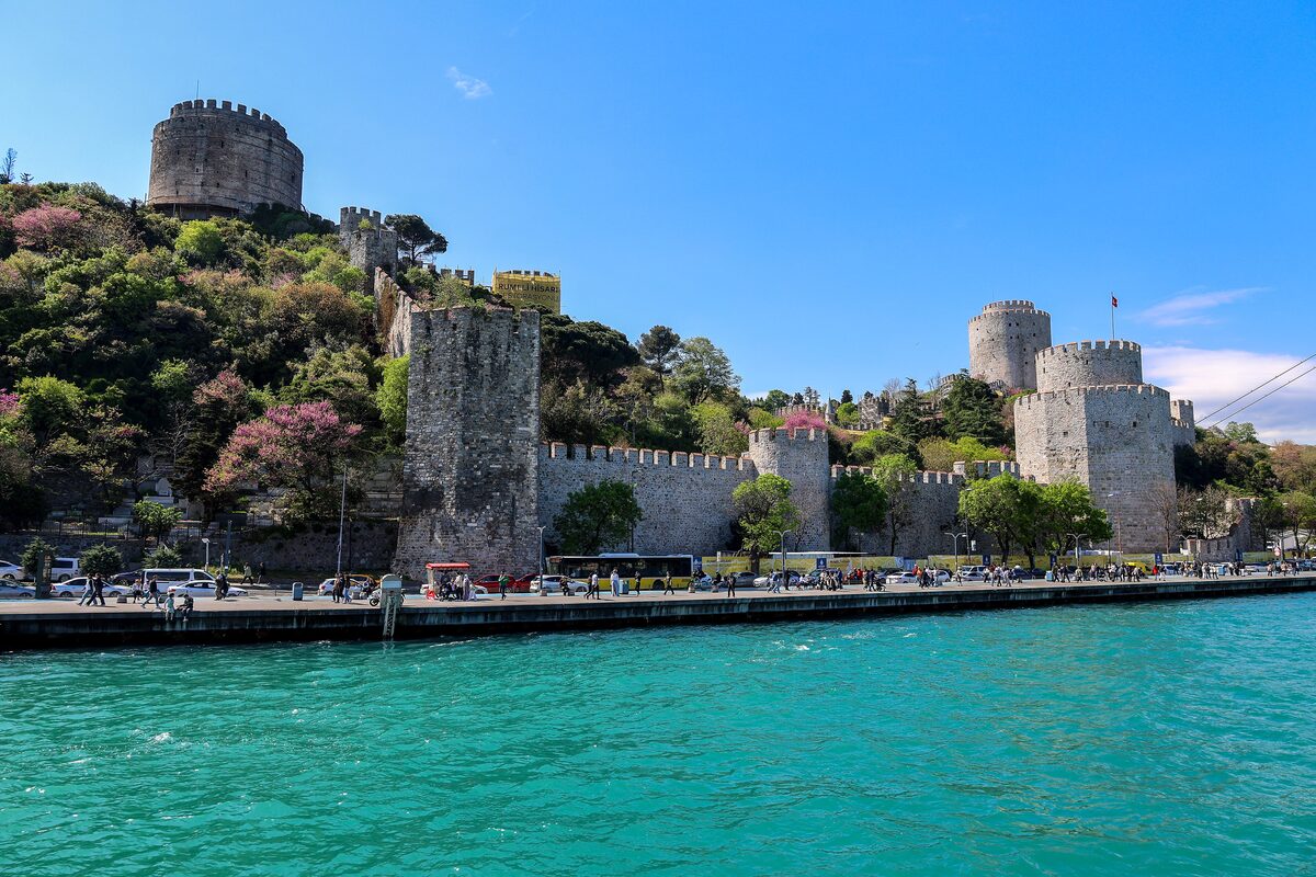 The walls and round towers of Rumeli Hisarı climbing a green hillside above the turquoise Bosphorus