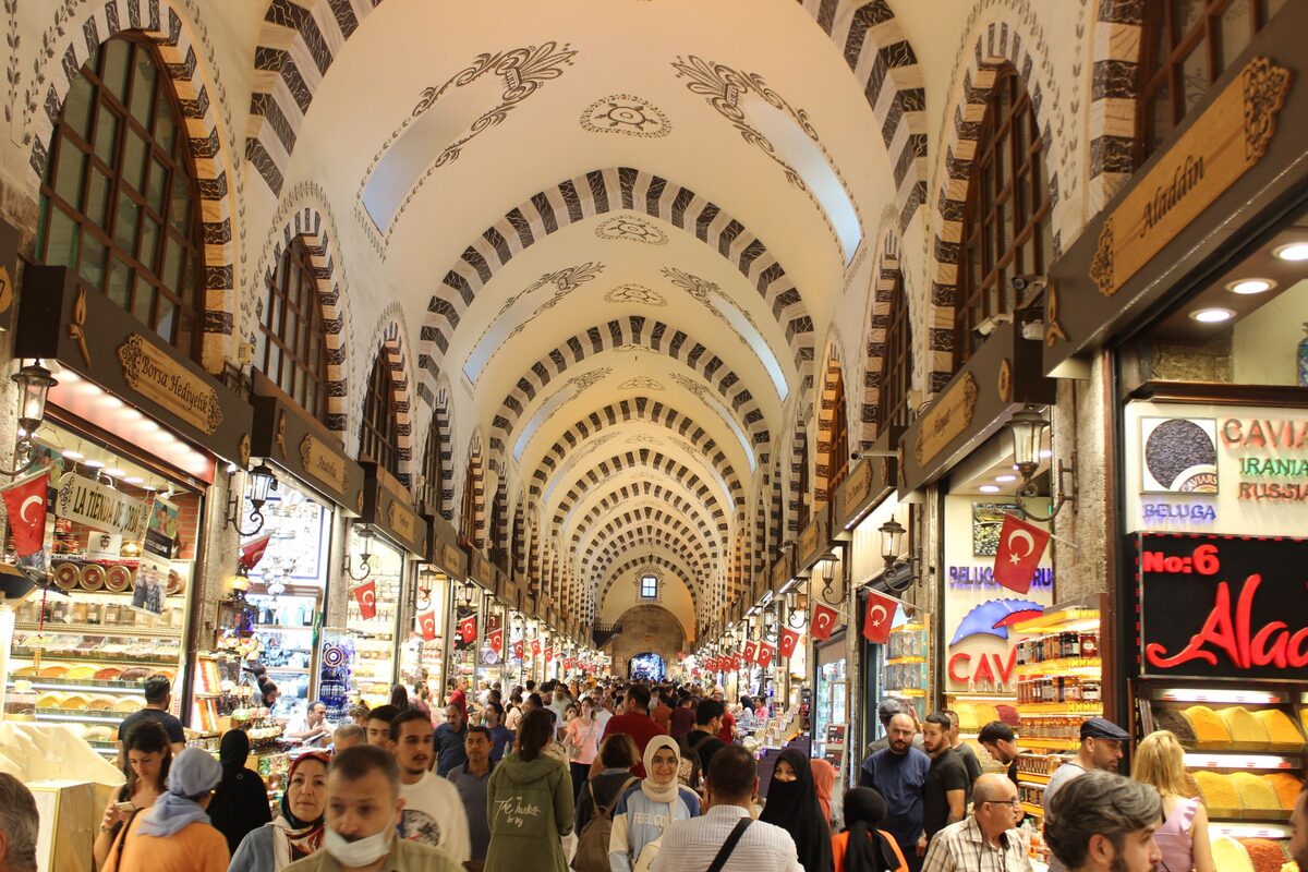 The long vaulted hall of the Spice Bazaar with striped arches, lit shopfronts and crowds of shoppers