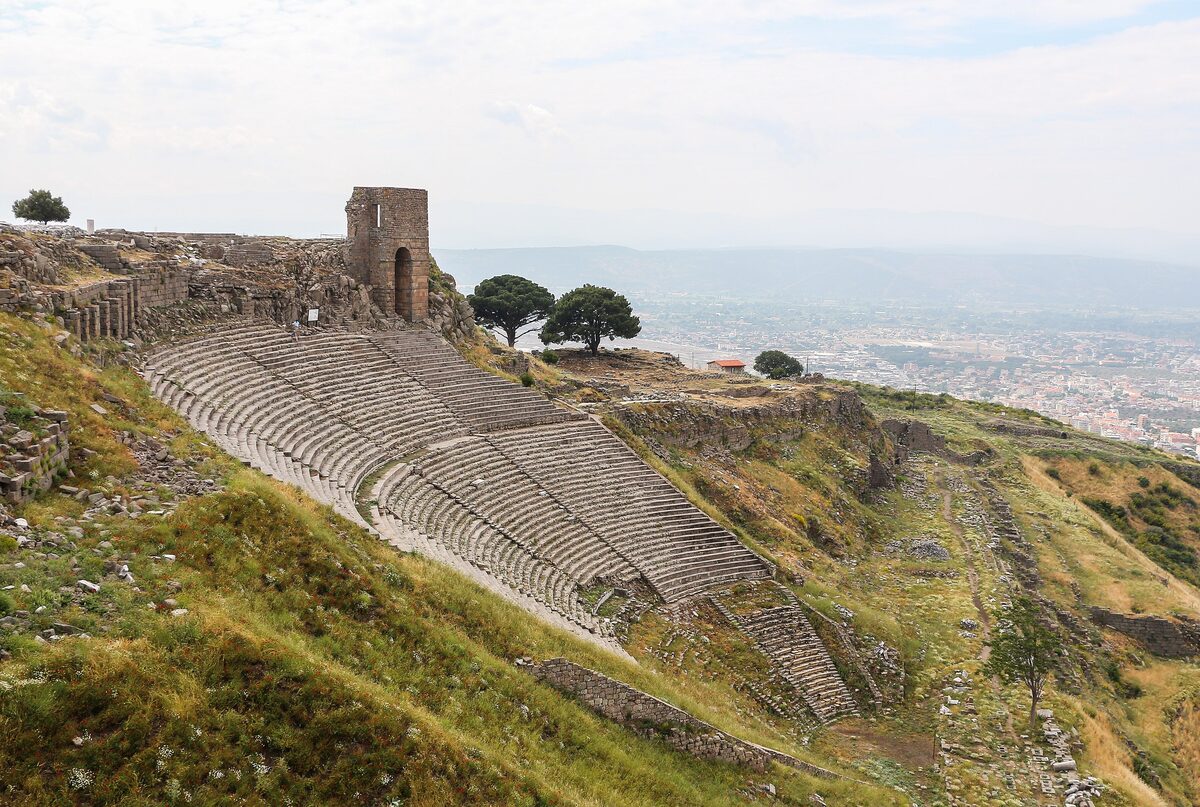 The steep stone seats of the theatre of Pergamon curving down the hillside, with the plain of Bergama far below