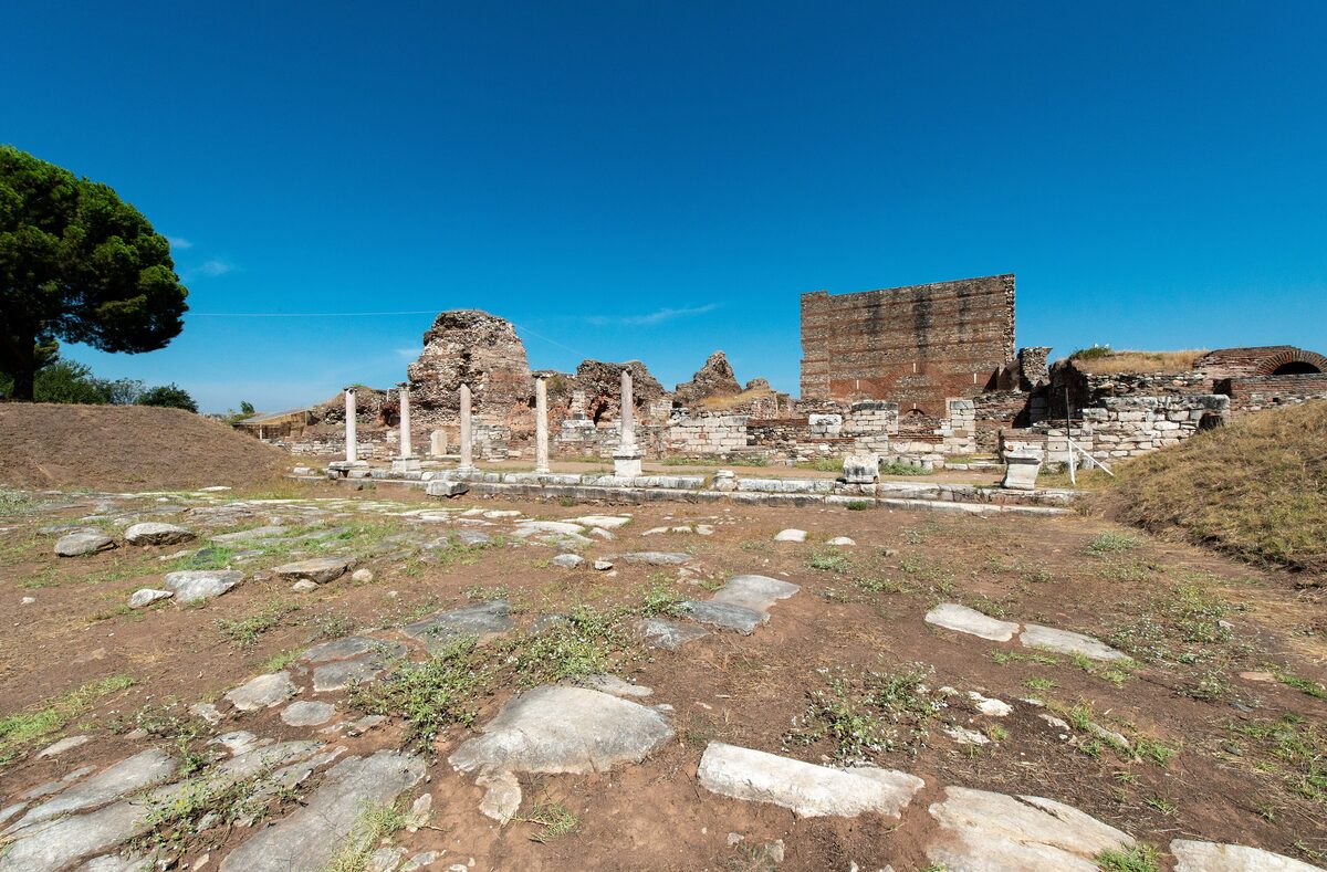 A Roman colonnaded street at Sardis with the tall restored walls of the bath and gymnasium complex behind it