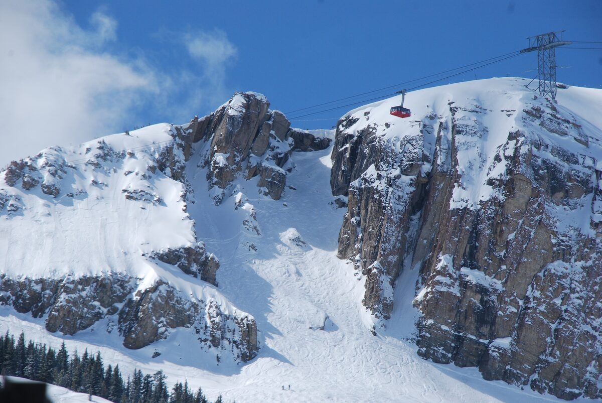 Corbet's Couloir, a steep snow-filled chute between rock walls, with a tram car on the ridge above