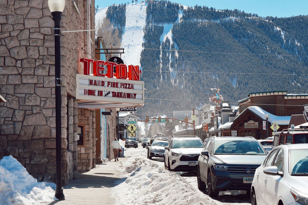 Cache Street in downtown Jackson in winter, looking south past the Teton Theatre sign to the wooded ski runs of Snow King Mountain